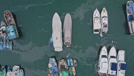 drone descending towards two motorboats docked in port with tarpaulin covering them in aberdeen, hong kong