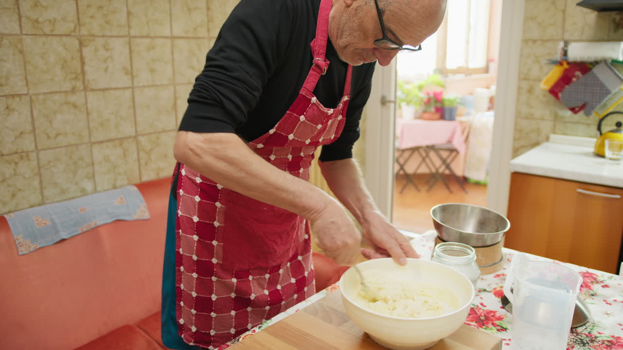Elderly Man Uses Spoon to Mix Dough Ingredients