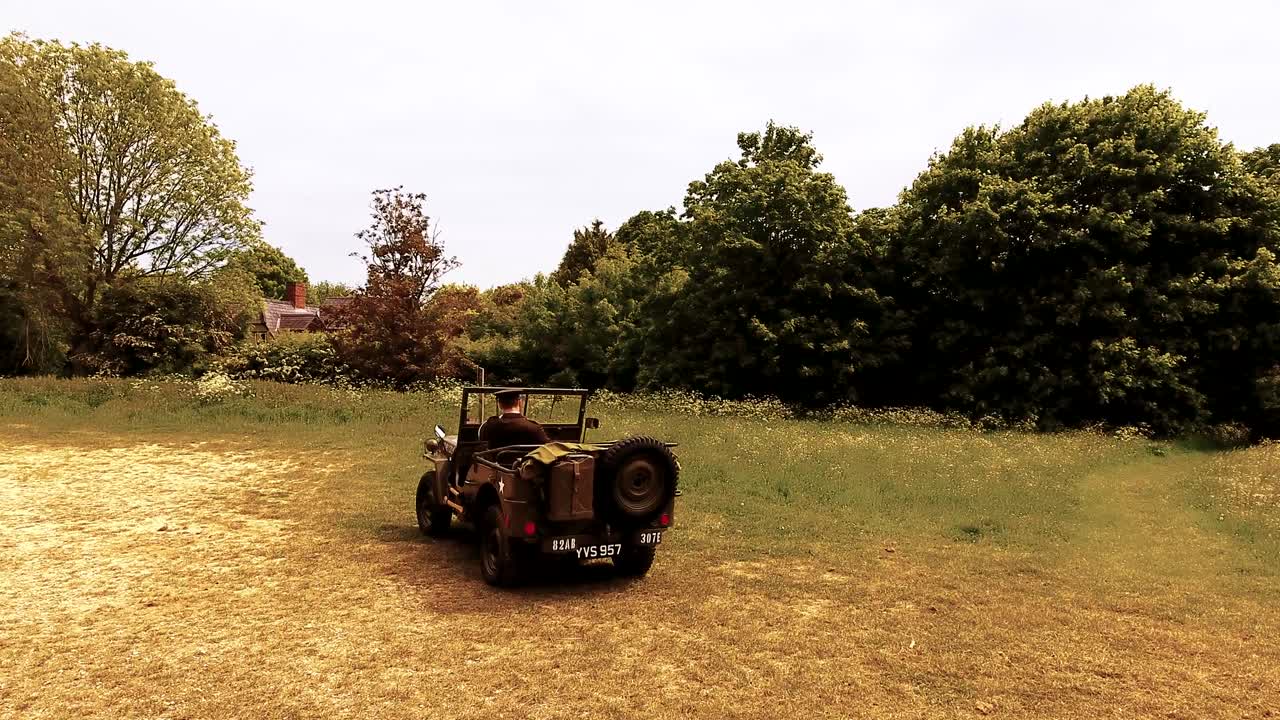 유니폼을 입은 잘생긴 미국 wwii gi 육군 장교는 윌리 지프에 서서 인사를합니다.