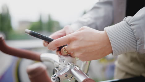 close up of woman on bike texting on mobile phone in skate park