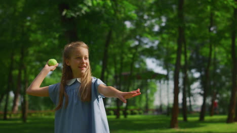 smiling girl throw ball on green meadow closeup. happy kid play catch in park.