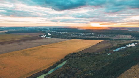 zonsondergang over landelijk landschap met velden, rivier en bos