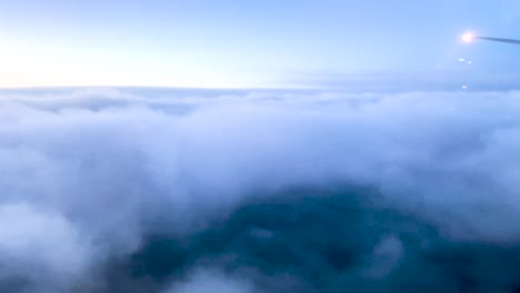 plane descending through thick blue clouds at blue