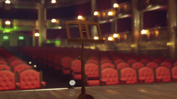 Empty stage with music stand and red seats in a theater