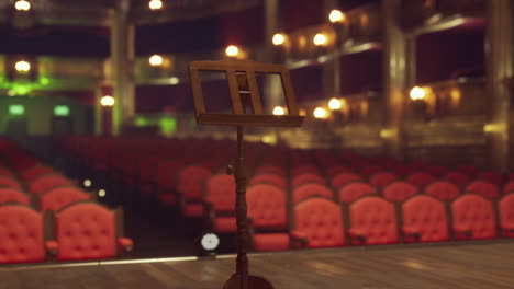 empty stage with music stand and red seats in a theater