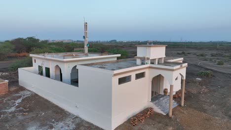 aerial profile view of newly constructed mosque with loudspeakers installed on the tower during daytime in a village near nawabshah, sindh , pakistan