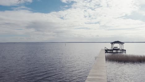 Vista-Al-Final-De-La-Tarde-A-Través-Del-Lago-Waccamaw-Con-Muelle-Y-Reflejos-Brillantes-De-Nubes