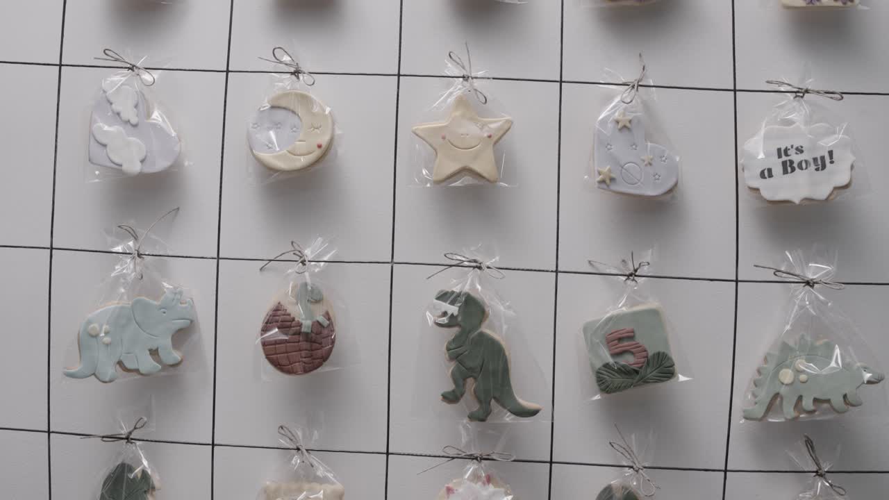 plano medio moviéndose hacia abajo de galletas de cumpleaños hechas a mano personalizadas colgadas en un estante en una pastelería haciendo regalos decorados individualmente, cámara lenta de 4k