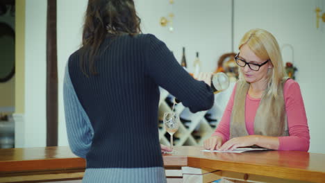 a woman tastes wine in a small winery communicates with the seller