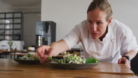 Caucasian-female-chef-preparing-a-dish-and-smiling-in-a-kitchen-