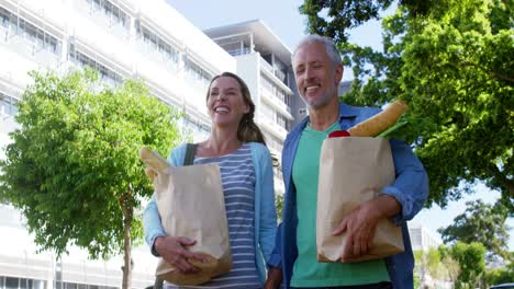 una pareja madura está sonriendo y caminando con comestibles