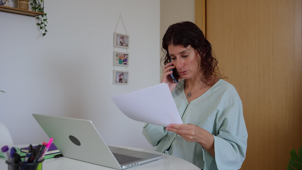 Mulher Falando ao Telefone e Revisando Documentos no Home Office