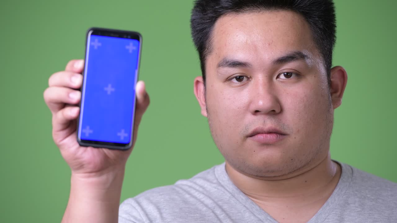 초록색 배경에 젊은 잘생긴 과체중 아시아인