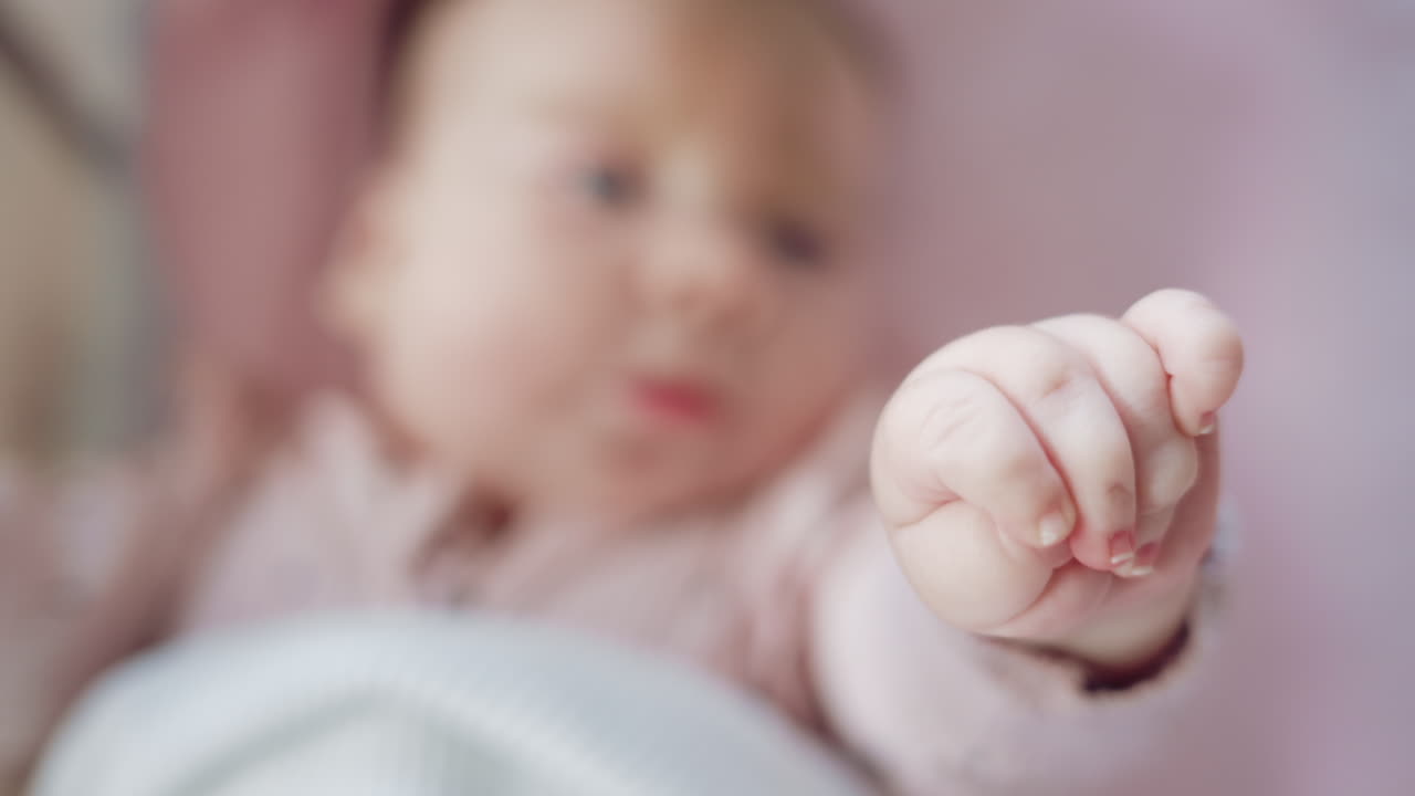 Close up of baby's tiny hand reaching out gently in soft pastel tones