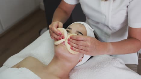 caucasian woman lying back while beautician gives her a facial