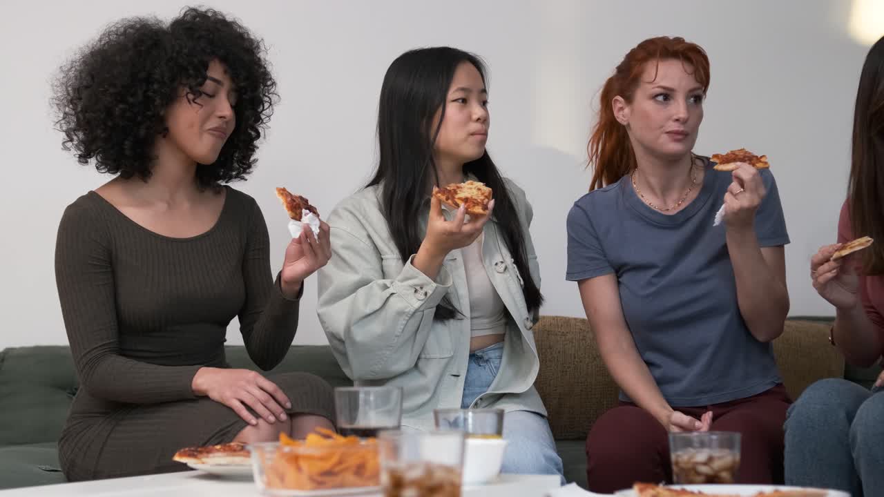 Diverse friends cheering up for woman bringing pizzas during weekend party at home
