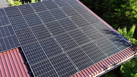 Solar panel rooftop on private home with green surroundings, close up aerial orbit view