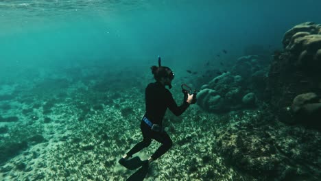 diver in wetsuit underwater capturing media of marine life and ascends