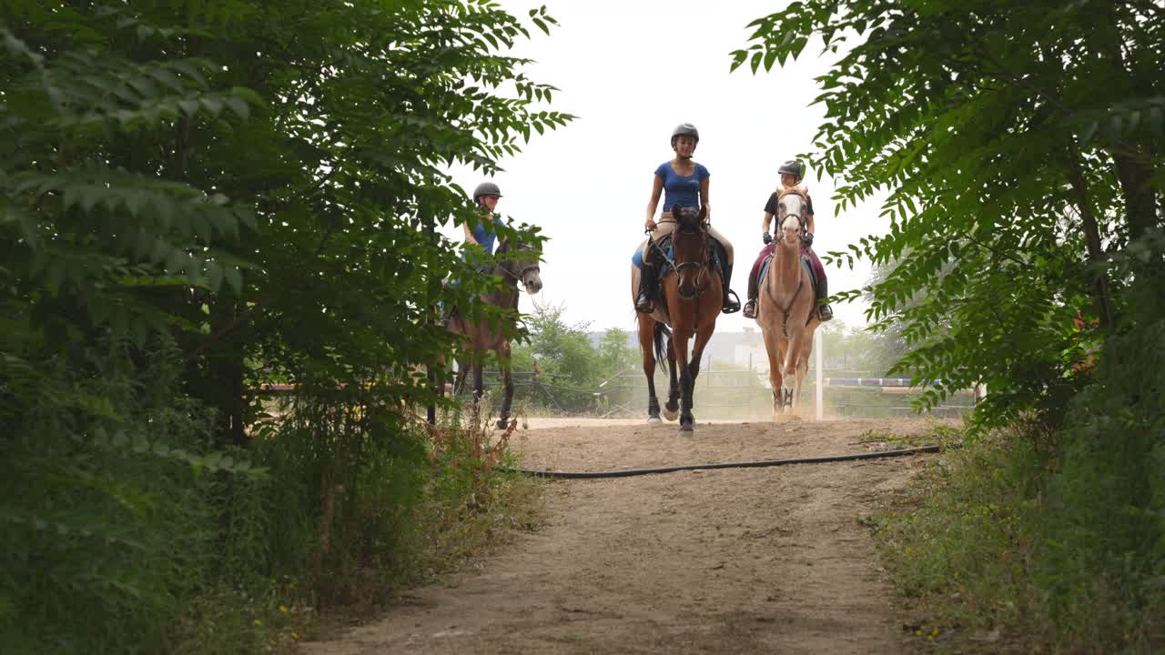 Three women riding horses leaving the track after finishing a jumping show
