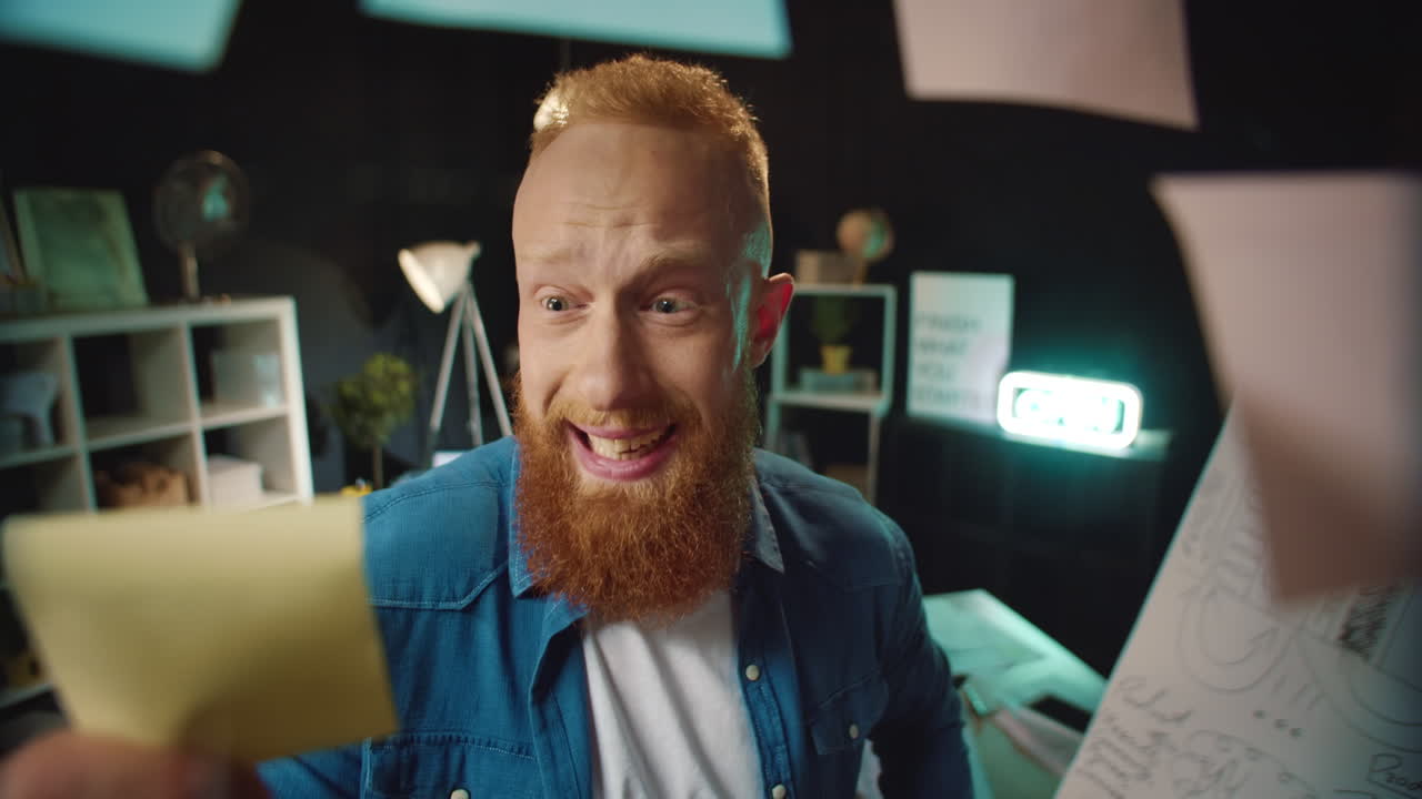 Ragazzo hipster felice che trova un adesivo con la soluzione giusta sulla lavagna in ufficio.