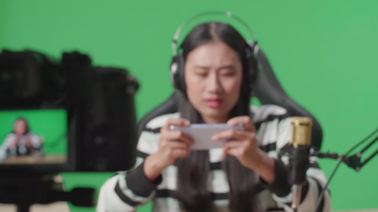 Close Up Of A Camera Monitor Recording Asian Woman Gamer With Headphone And Computer Losing Mobile Phone Game On The Green Screen Background