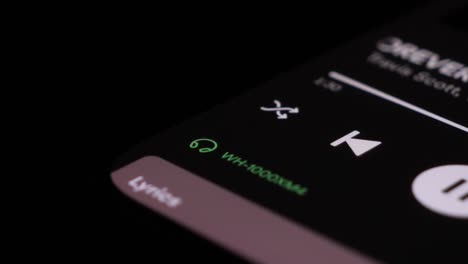 Close-Up-Shot-Of-Icons-Showing-Bluetooth-Connection-To-Wireless-Headphones-On-Spotify-App-On-Mobile-Device