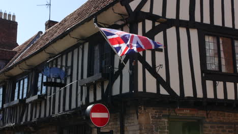 un viejo pub tudor británico con puerta de entrada de bar y bandera de union jack volando afuera