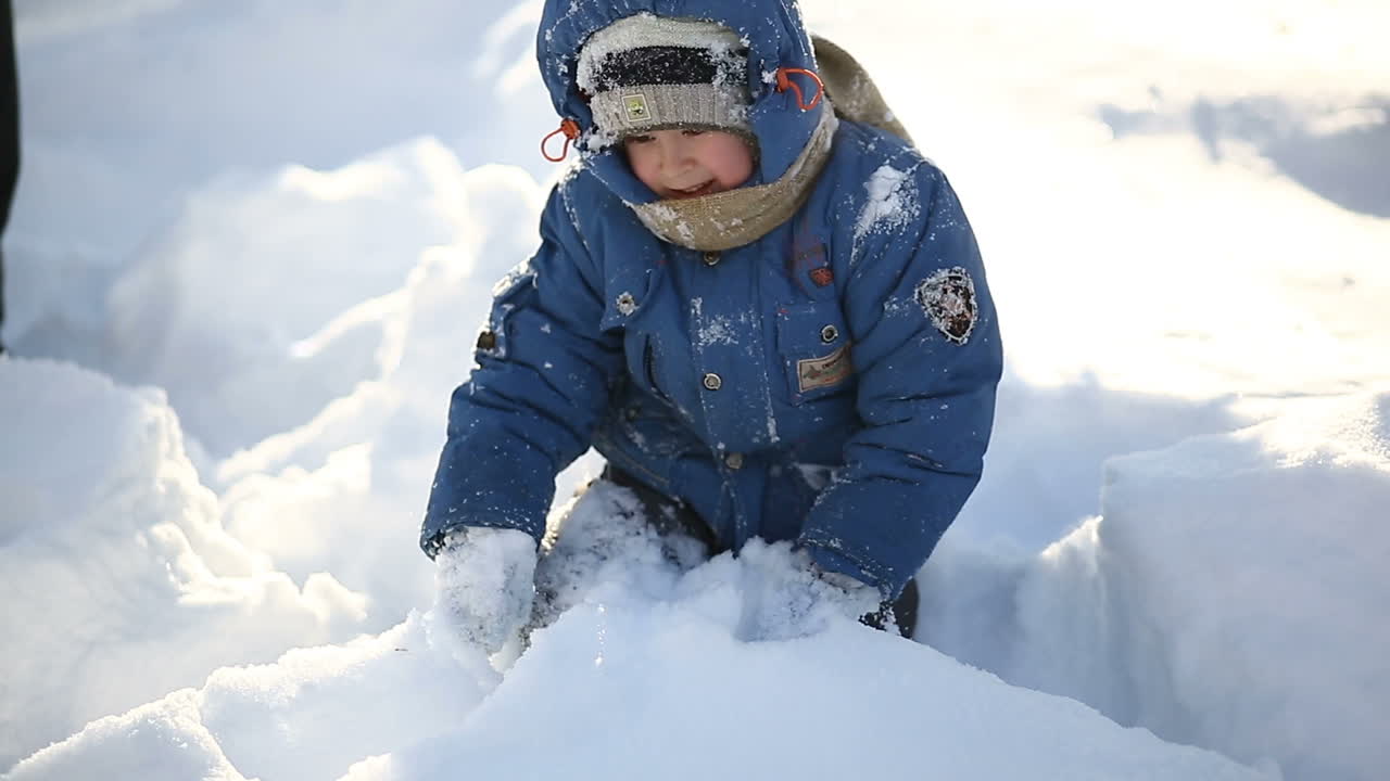 Boy playing in winter. Little boy walking outdoor in the winter time and playing with snow