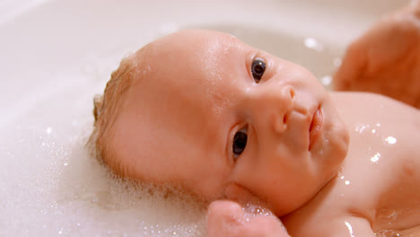 Mother-giving-her-baby-boy-a-bath-in-bathroom-at-home-4k