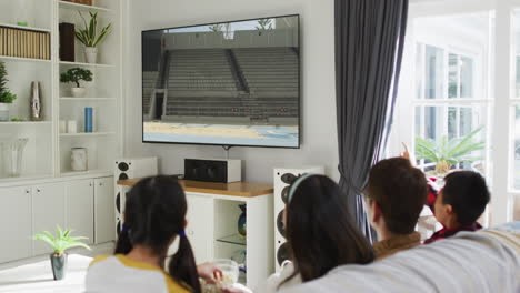 행복 한 가족 이 집 에서 함께 앉아서 tv 에서 장거리 점프 경기를 시청 하고 있다
