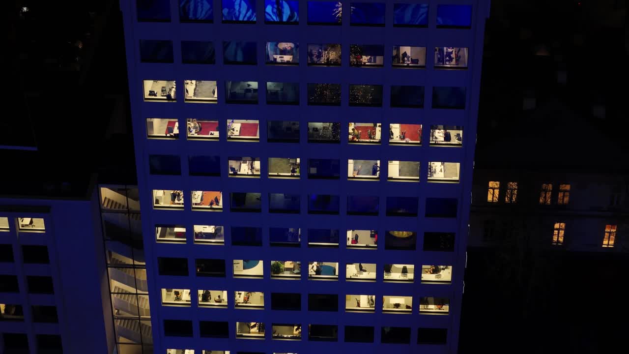 edificio de oficinas moderno con luces en el interior por la noche, vista de órbita aérea