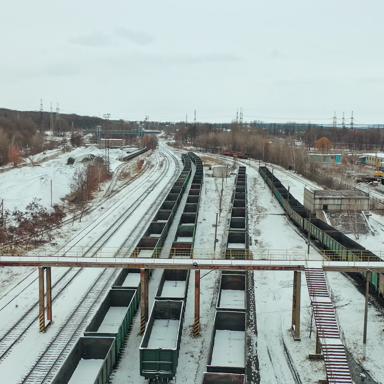 Long rows of containers stand on rails on the territory of the railway. Shipping. Camera motion to back. Aerial view.