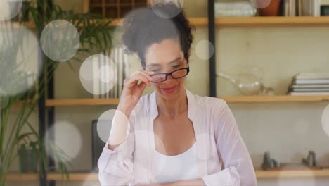 Animation-of-white-spots-of-light-over-biracial-woman-talking-to-camera