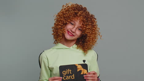 teenager girl showing pointing on gift discount certificate voucher coupon for store holidays sale