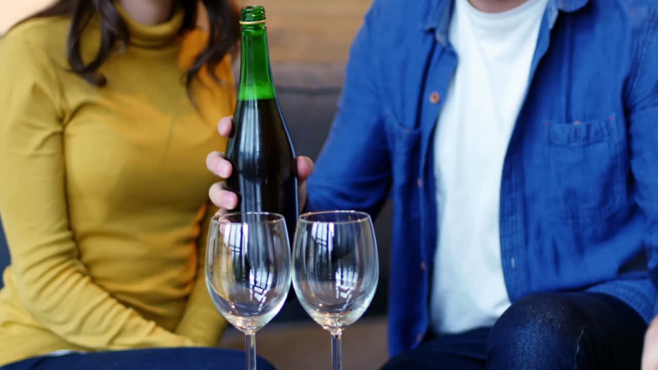 hombre sonriente vertiendo vino en vaso de vino