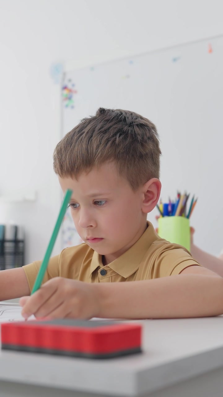 Niño concentrado dibujando con un lápiz en un aula