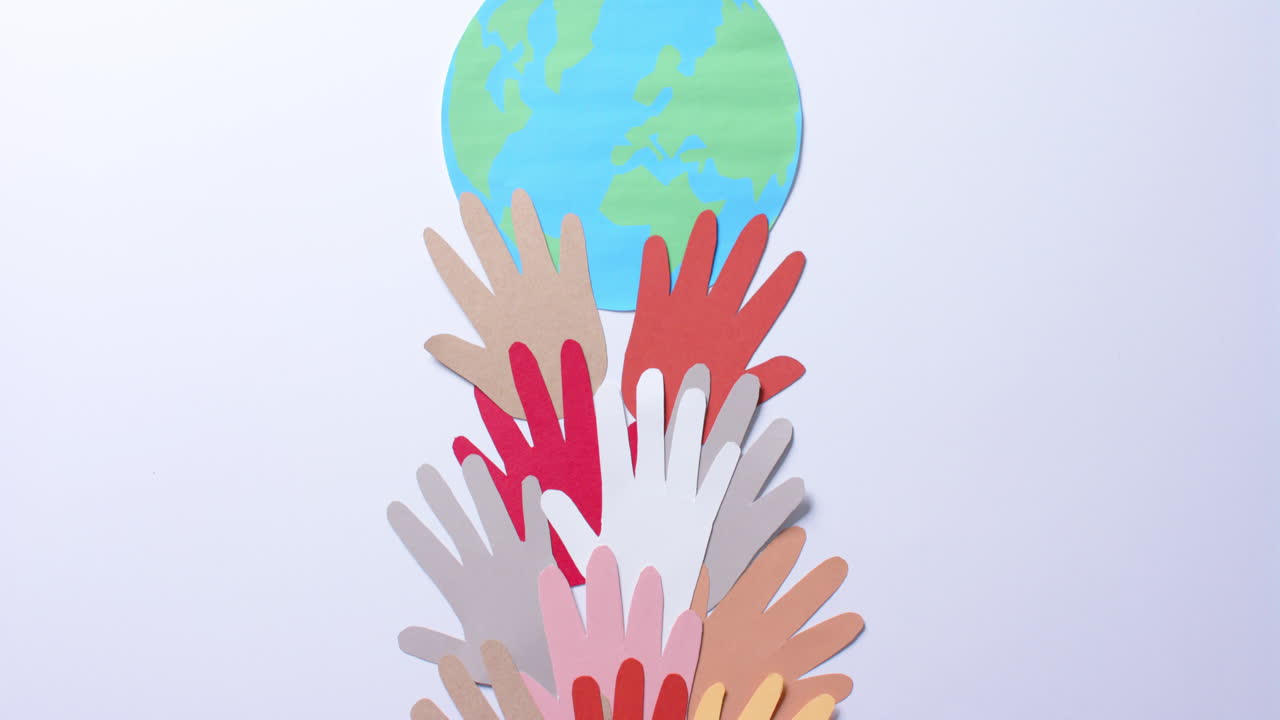 Close up of hands together with globe made of colourful paper on white background with copy space
