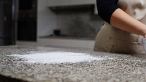 slow motion of woman dusting flour on granite countertop close-up.