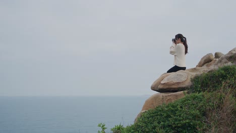 side view of a woman sitting on a cliff