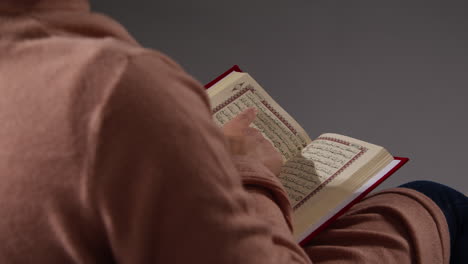 close up of muslim woman sitting on sofa at home reading or studying the quran 2