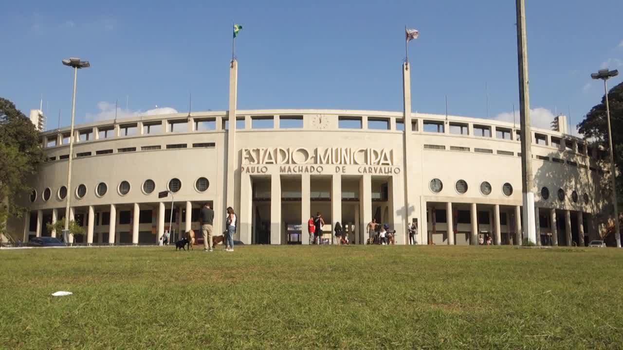 city residents and dogs enjoying the sunny day on the square in front of the Pacaembu Stadium. Low angle view
