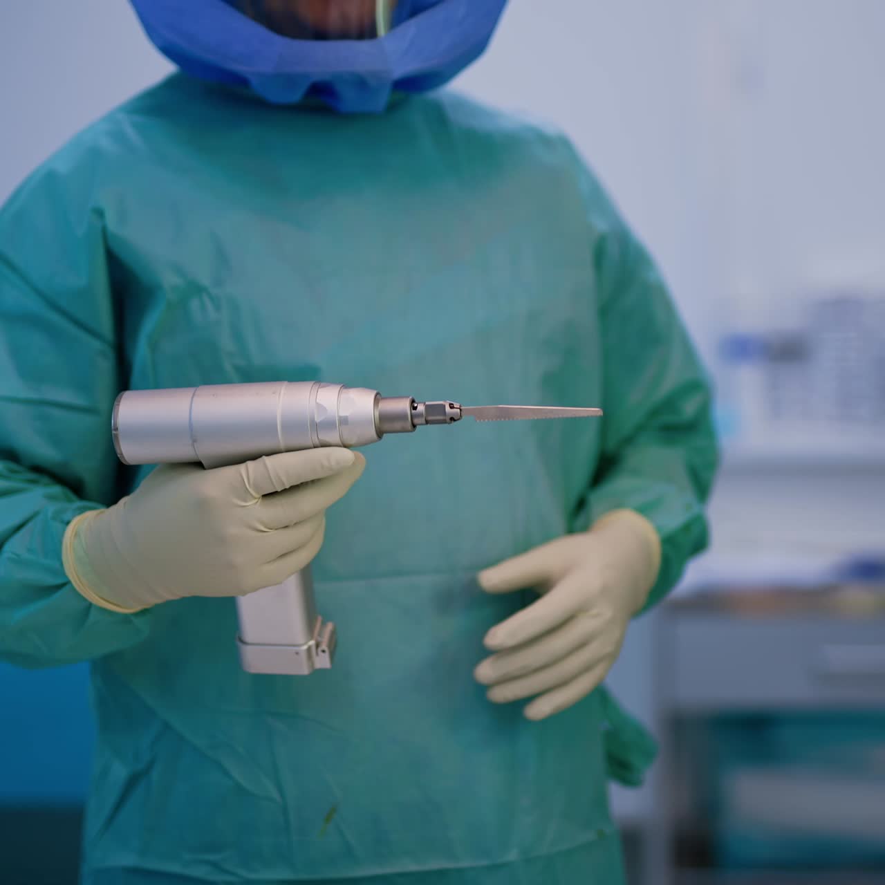 Unrecognized doctor holding a reciprocating surgical saw. Orthopedic device for bone cutting in the hands of a surgeon