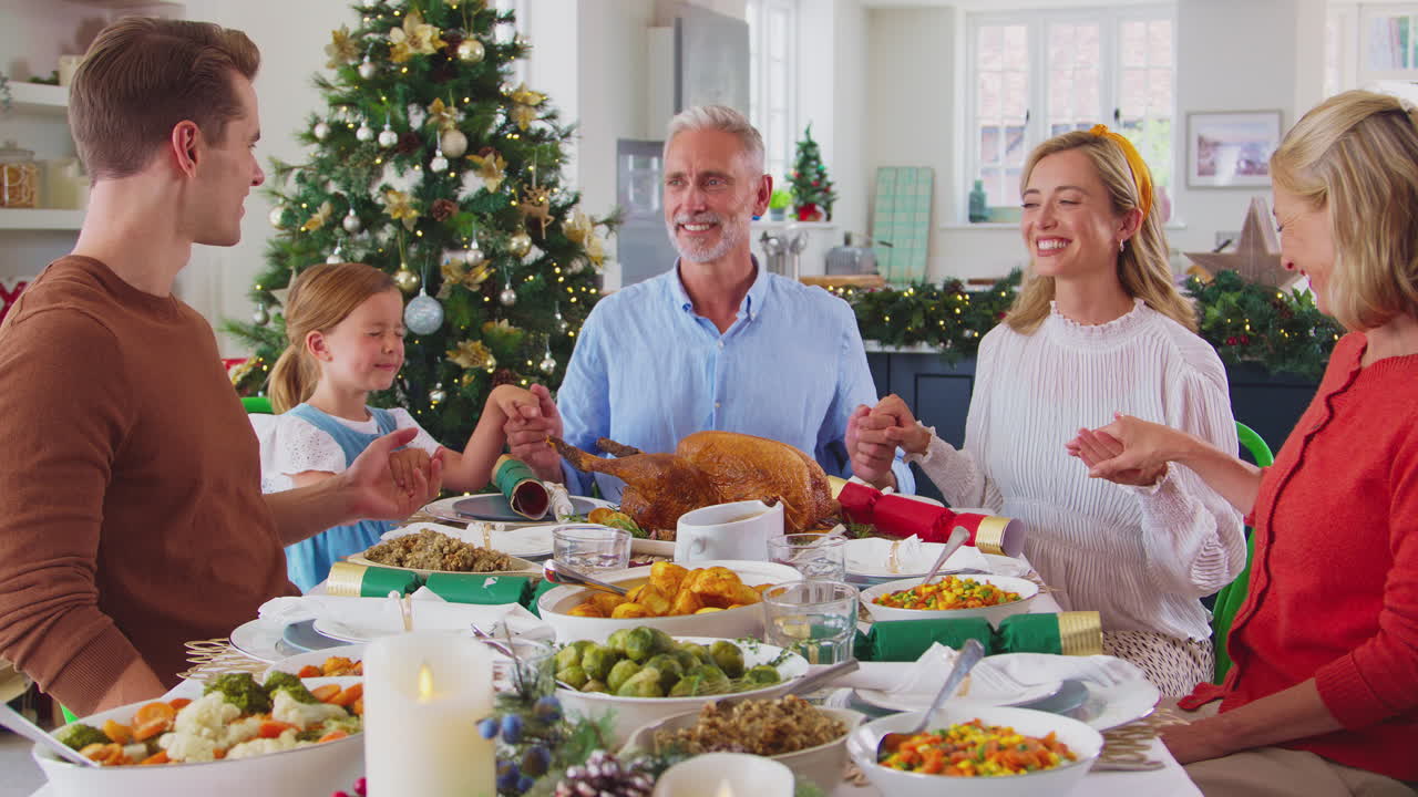 집에서 크리스마스를 축하하는 다세대 가족은 함께 식사를 하기 전에 기도를 합니다.