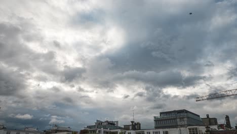 an immersive time lapse of dark swirling low level nimbostratus, stratus and cumulus clouds pass over rooftops and buildings during a summer thunderstorm