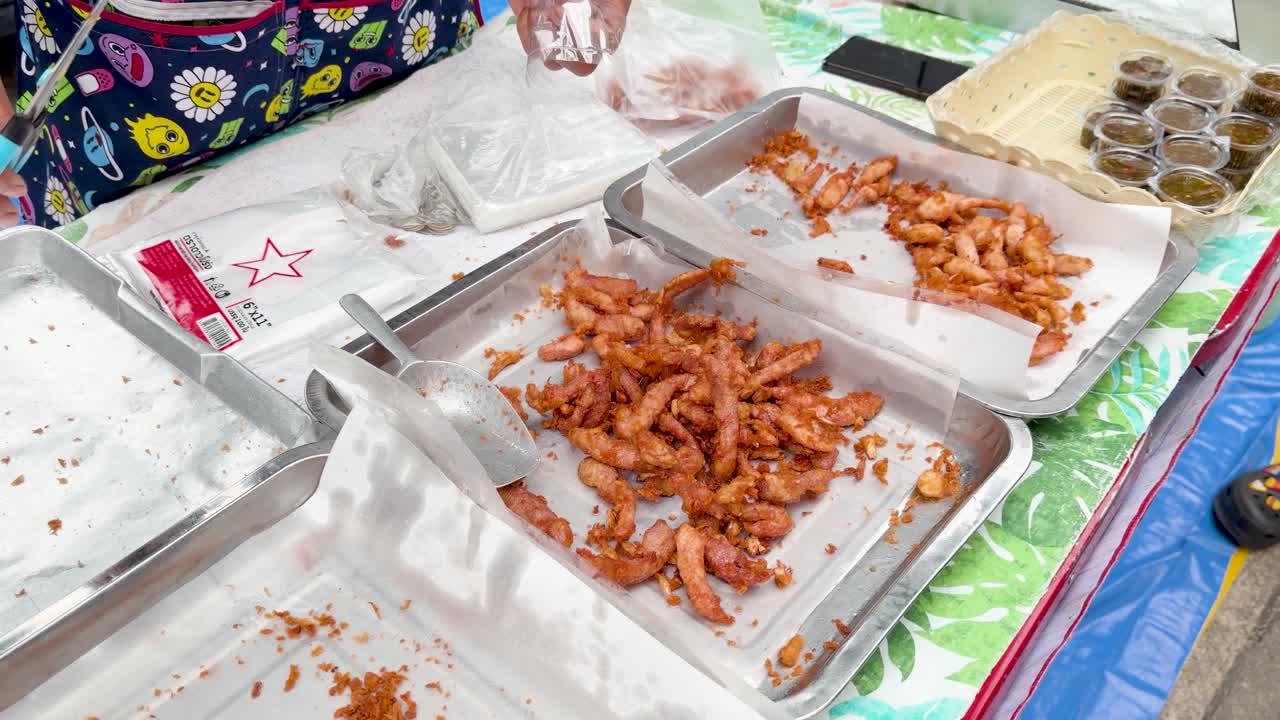Vendor cuts fried chicken with scissors at colorful Bangkok street food market stall