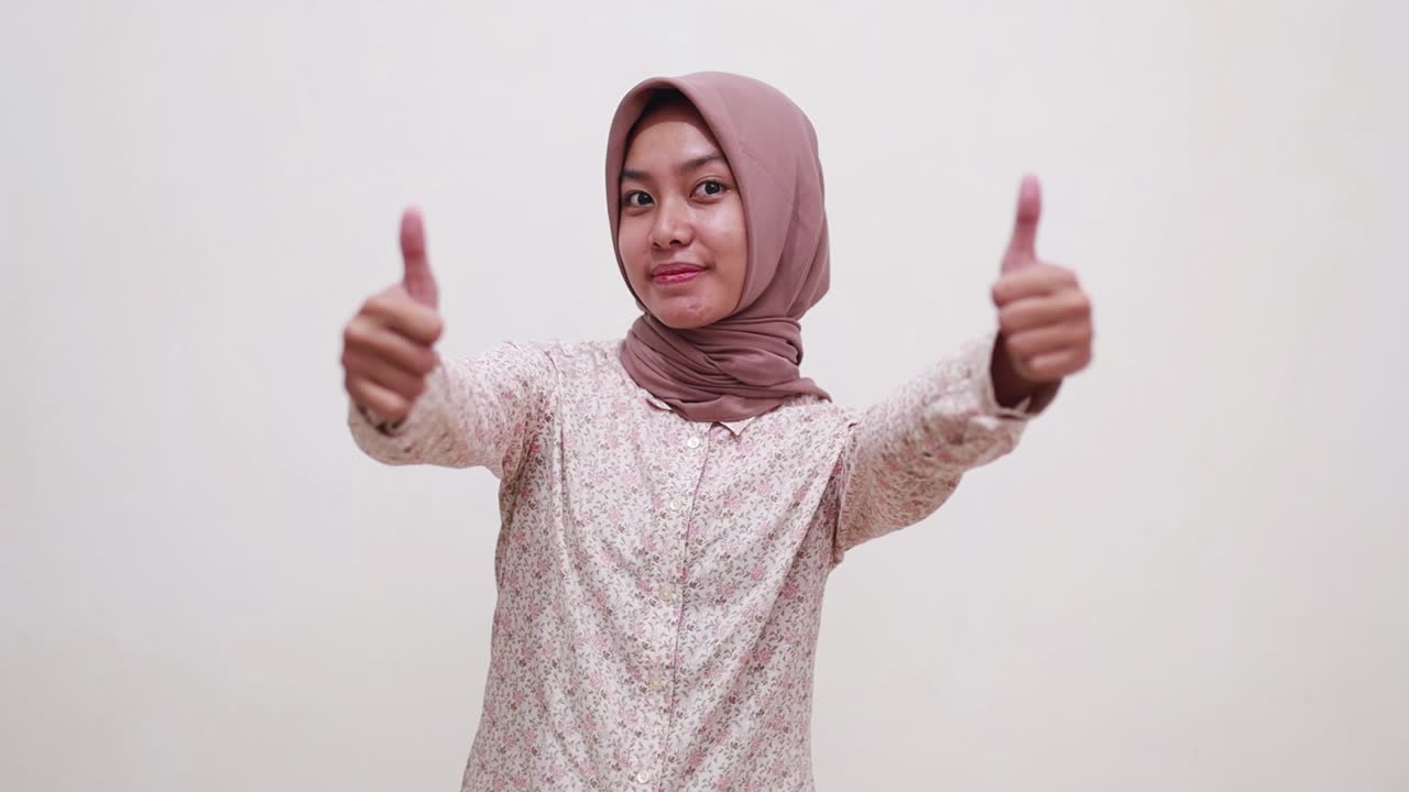 기분 좋은 젊은 아시아 무슬림 소녀 가 엄지 손가락 을 올려놓고 서 있다