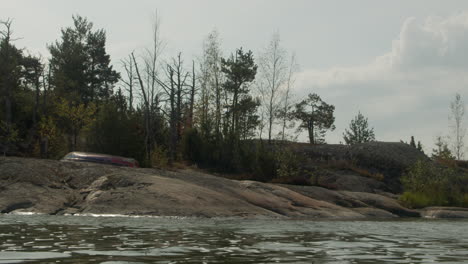 Viejo-Bote-De-Remos-En-Una-Playa-De-Isla-Rocosa-En-El-Archipiélago-Finlandés-Con-Suaves-Olas-Y-Ambiente-Relajante-4k