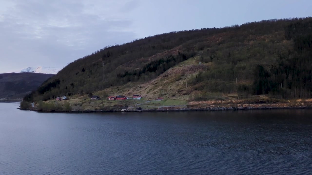 Norsk fjordlandskab med røde huse på en skovklædt bjergside.