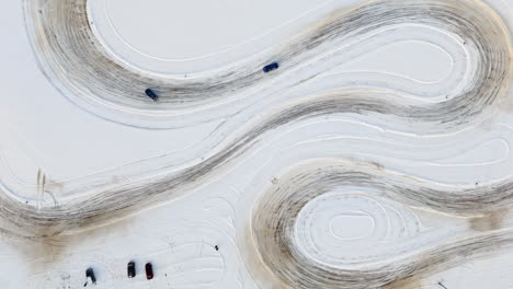 cenital aerial view following cars racing on a ice track, sunny, winter day