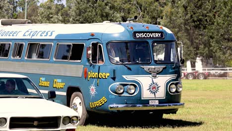 old-fashioned bus moves through grassy area